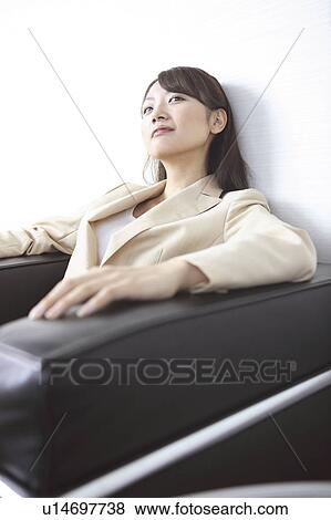 Stock Photo - Office lady sitting on a sofa. Fotosearch