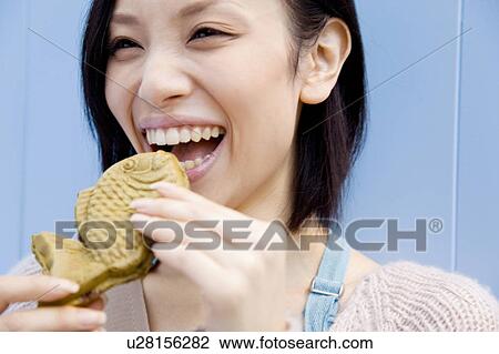 Stock Image - Woman eating a Taiyaki. Fotosearch