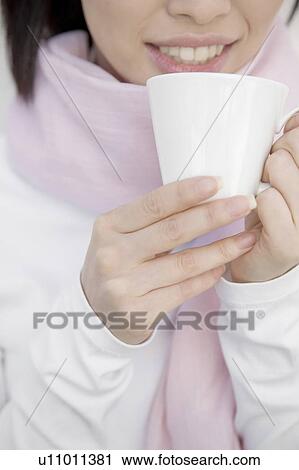 Stock Image - Woman gripping a coffee cup. Fotosearch