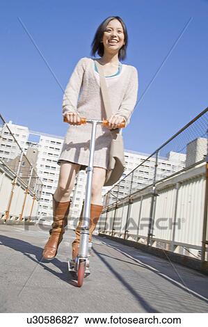 Stock Photo - Woman riding a kick scooter. Fotosearch