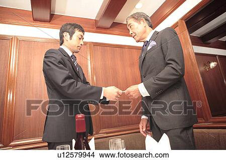 Picture - Japanese office workers exchanging business cards. Fotosearch