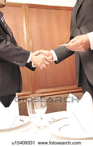 Stock Image - Office workers shaking hands. Fotosearch