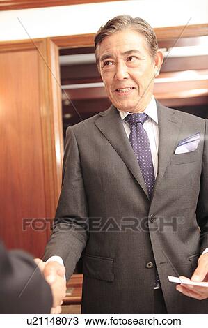 Stock Image - Office workers shaking hands. Fotosearch