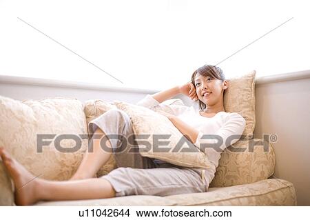 Picture - Japanese woman relaxed on the sofa. Fotosearch