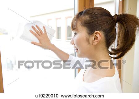 Stock Image - Japanese woman wiping window. Fotosearch