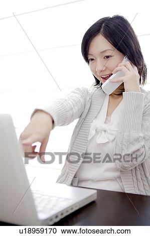 Stock Image - Office lady talking on a cell phone. Fotosearch