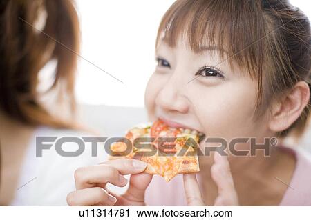 Stock Image - Young woman eating pizza. Fotosearch