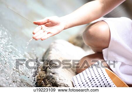 Stock Photo - Hand of woman scooping the water of the hot spring. Fotosearch
