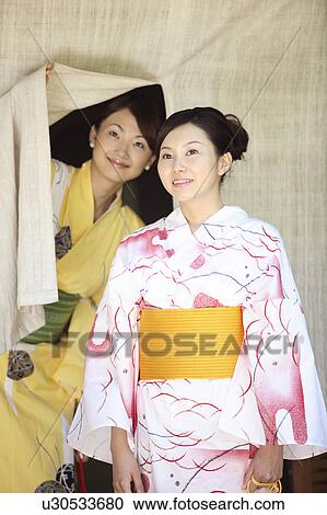 Stock Image - Japanese woman putting on a yukata. Fotosearch