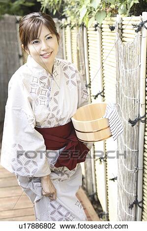 Stock Image - Japanese woman putting on kimono. Fotosearch