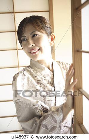 Stock Photo - Japanese woman putting on kimono. Fotosearch