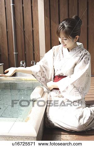 Stock Image - Japanese woman scooping the hot water of the hot spring. Fotosearch