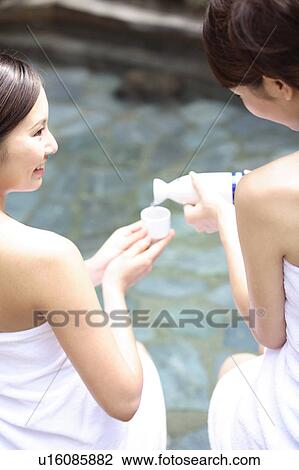 Stock Image - Japanese women drinking sake in a open-air bath. Fotosearch