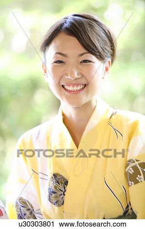 Stock Image - Woman putting on a yukata. Fotosearch