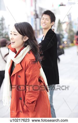 Stock Image - Japanese young woman pulling boyfriend's hand. Fotosearch