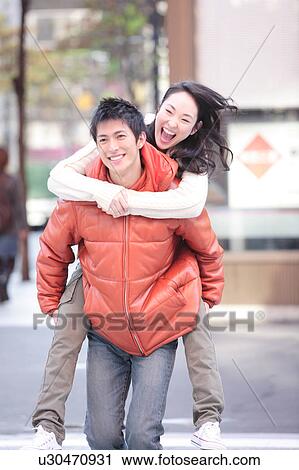 Stock Image - Young couple being playful on a city street. Fotosearch