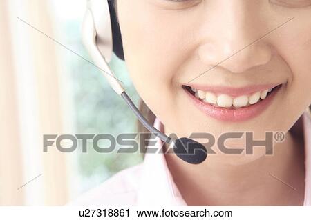 Stock Image - Office lady talking with headset. Fotosearch