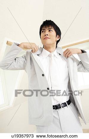 Stock Image - Office worker putting on a jacket. Fotosearch