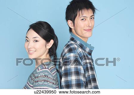 Stock Image - Couple standing back to back. Fotosearch
