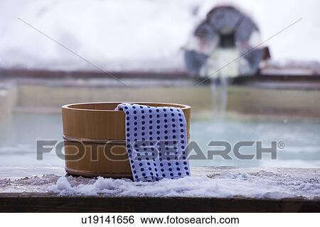 Stock Photograph - Hot spring beside towel on wooden tub beside hot spring. Fotosearch