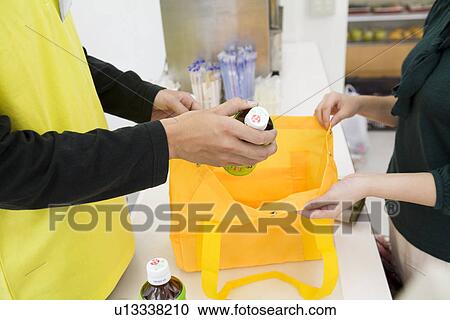 Stock Image - Clerk and customer at convenience store. Fotosearch