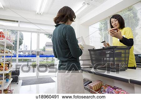 Stock Image - Clerk and customer at convenience store. Fotosearch