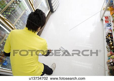Stock Image - Convenience store clerk cleaning up store. Fotosearch