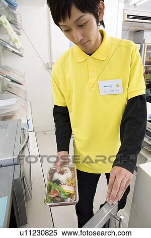 Stock Photography - Convenience store clerk holding lunchbox. Fotosearch