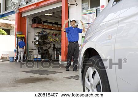 Stock Photo - Gas station clerk guiding car. Fotosearch