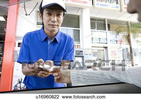 Stock Image - Gas station clerk receiving card from customer. Fotosearch