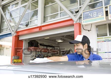 Stock Image - Gas station clerk washing car . Fotosearch