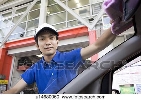 Stock Image - Gas station clerk wiping car window. Fotosearch