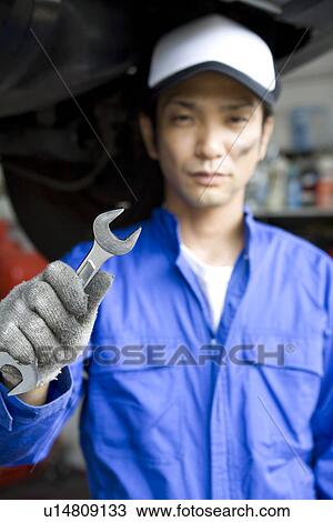 Stock Image - Mechanic holding wrench. Fotosearch