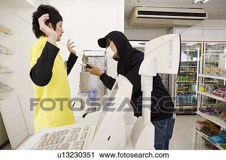 Stock Image - Robber threatening convenience store clerk . Fotosearch