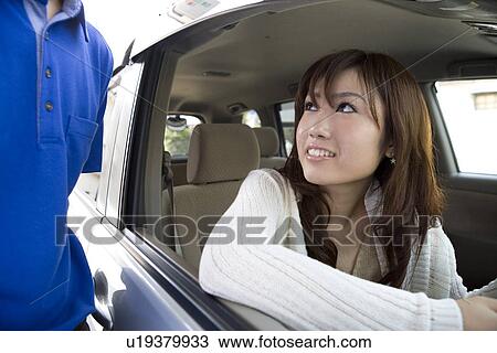 Stock Image - Young woman in car and gas station clerk. Fotosearch