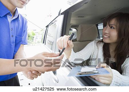 Stock Photography - Young woman in car handing pen and holder to gas station clerk . Fotosearch