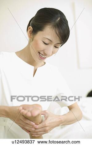 Stock Photo - Massage therapist applying foot massage. Fotosearch