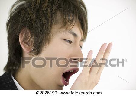 Stock Photo - Young businessman checking his breath. Fotosearch