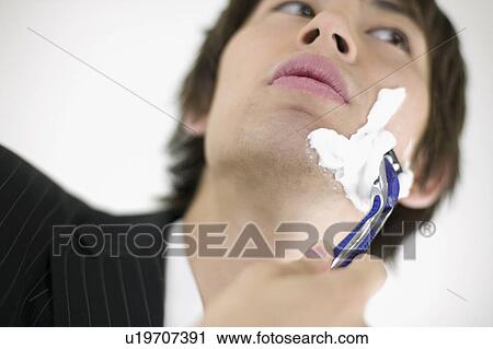 Stock Image - Young businessman shaving. Fotosearch