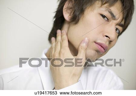 Stock Image - Young businessman worrying about his beards. Fotosearch