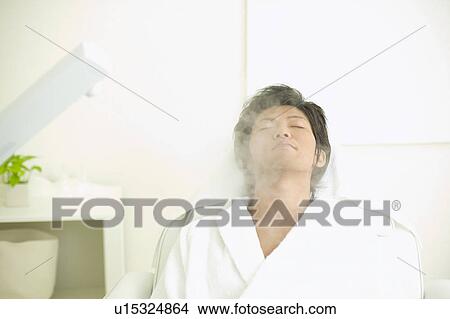 Picture - Young man receiving esthetic facial steam. Fotosearch