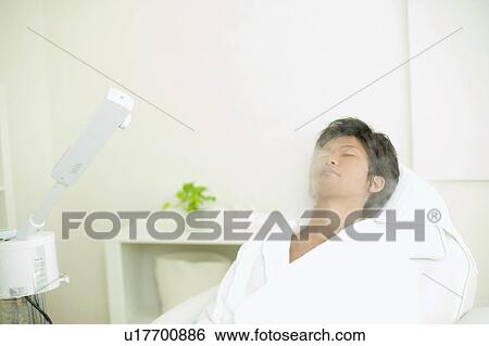 Stock Photograph - Young man receiving esthetic facial steam. Fotosearch