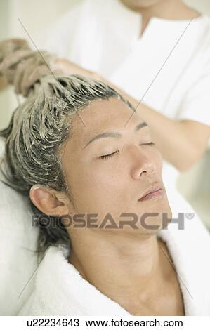 Stock Image - Young man receiving hair restoration massage. Fotosearch