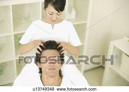 Stock Photo - Young man receiving hair restoration massage. Fotosearch