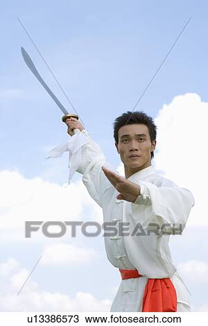 Stock Image - Man practicing martial arts with swords. Fotosearch