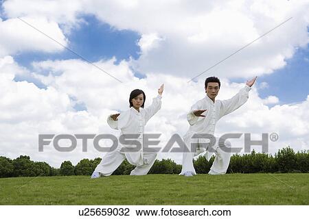 Stock Image - Young man and woman in the same martial arts pose. Fotosearch