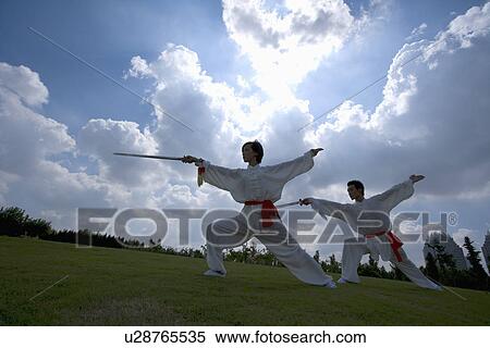 Young man and woman practicing martial arts against cloudy sky View Large Photo Image Stock Photography - Young man and woman practicing martial arts against cloudy sky. Fotosearch