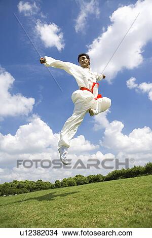 Young man doing kung-fu moves in mid air View Large Photo Image Picture - Young man doing kung-fu moves in mid air. Fotosearch