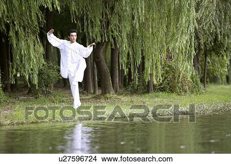Picture - Young man doing martial arts at the water's edge. Fotosearch
