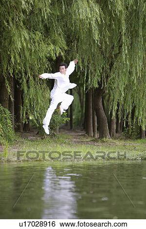 Stock Photograph - Young man in martial arts pose at water's edge. Fotosearch